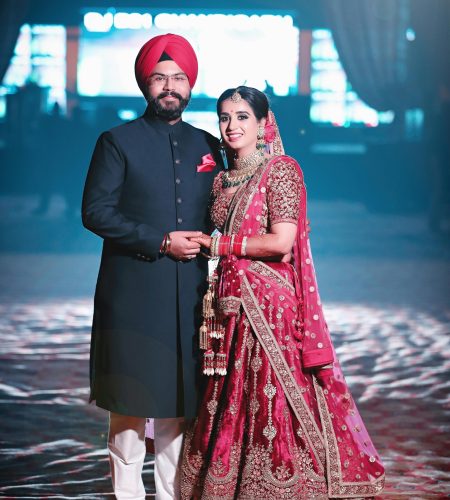 A joyful Indian couple in traditional wedding attire, celebrating their special day indoors.